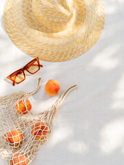 Vintage inspired background with straw hat, female sunglasses and shopper bag with peaches on white...