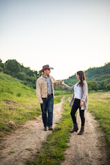 A Caucasian heterosexual couple walks down the alley, holding hands, near a picturesque village in Ukraine. Vertical photo.