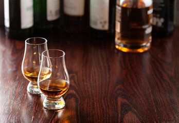 Bottles and glass of whisky spirit brandy on dark brown background