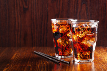 glass of cold cola soft drink with ice on wooden background