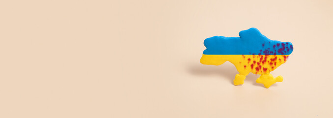 Plasticine yellow and blue map of Ukraine with shots in the blood with copy space banner format....