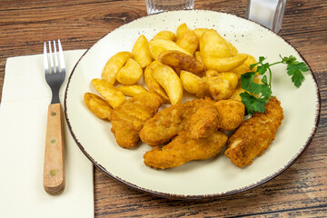 potato and cooked chicken nuggets in a plate on a table