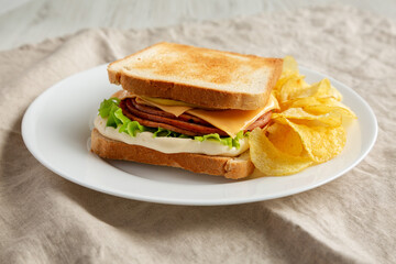 Homemade Fried Bologna and Cheese Sandwich with Chips on a Plate, low angle view.