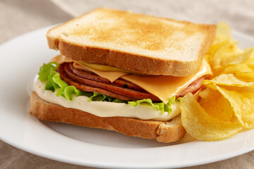 Homemade Fried Bologna and Cheese Sandwich with Chips on a Plate, side view.