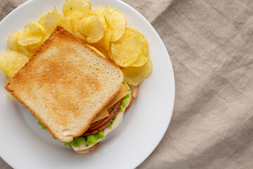 Homemade Fried Bologna and Cheese Sandwich with Chips on a Plate, top view. Flat lay, overhead, from above. Copy space.