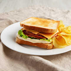 Homemade Fried Bologna and Cheese Sandwich with Chips on a Plate, side view.