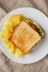 Homemade Fried Bologna and Cheese Sandwich with Chips on a Plate, top view. Flat lay, overhead, from above.