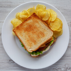 Homemade Fried Bologna and Cheese Sandwich with Chips on a Plate, top view. Flat lay, overhead, from above.
