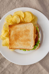 Homemade Fried Bologna and Cheese Sandwich with Chips on a Plate, top view. Flat lay, overhead, from above.