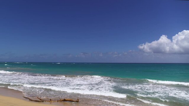 Sea sandy Cuban beach on a summer sunny day. Ocean waves on the sand of a tropical coast. White clouds in the blue sky over the turquoise sea. Landscape of wild nature. Cruise.