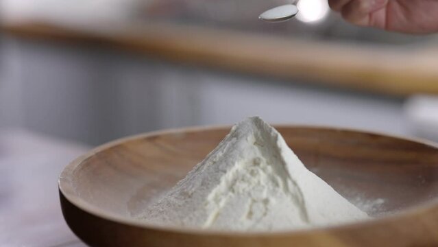 Adding sugar or salt to some flour in a stylish kitchen slow motion 100 fps