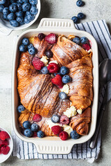 Croissant baked french toast with cream cheese and berries in a dark oven dish. Delicious breakfast...