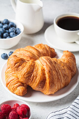Delicious breakfast with croissants, coffee and berries, gray background.