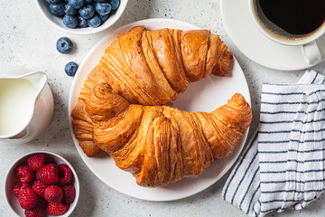 Delicious breakfast with croissants, coffee and berries, gray background.