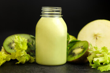 Fresh green smoothie in a plastic bottle  on a black background. Celery, apples, kiwi and mint. Superfoods, detox, diet, healthy food.
