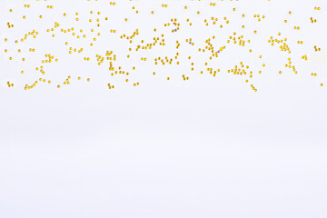 Golden shiny particles on a white background. The perfect backdrop for your presentation. Copy space
