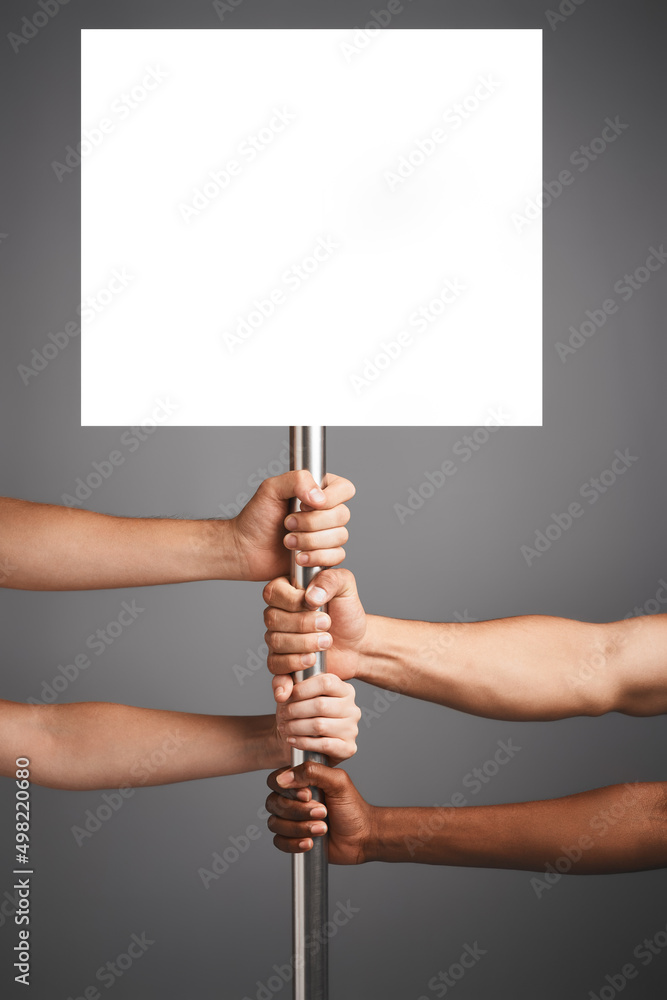Aufkleber well get our point across. studio shot of unidentifiable hands holding on to a poster against a gray