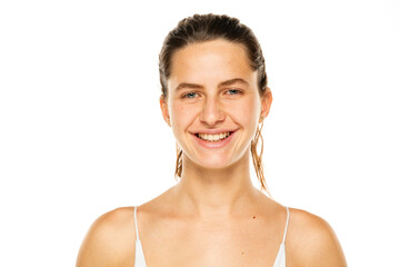 Portrait of a young smiling woman with tied hair and without makeup on a white background