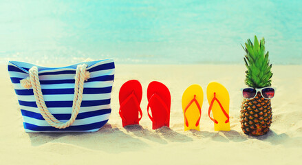 Summer vacation concept - bag and flip flops on beach over blue sea background