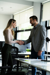 Colleagues heandshake in office. Businesswoman and businessman discussing work in office