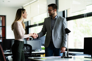 Colleagues heandshake in office. Businesswoman and businessman discussing work in office