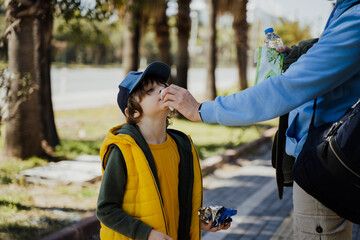 Father helps little son to blow his nose with the nandkerchief. Dad wiping boy's nose with...