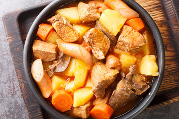 Pork Menudo is a type of Filipino stew cooked with pork meat,  liver and vegetable close up in the plate on the table. Horizontal top view from above