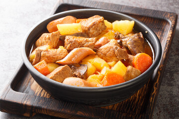 Tasty Pork Menudo is a Filipino stew dish that is typically made with pork, liver, tomatoes, potatoes, and other vegetables close up in the plate on the table. Horizontal