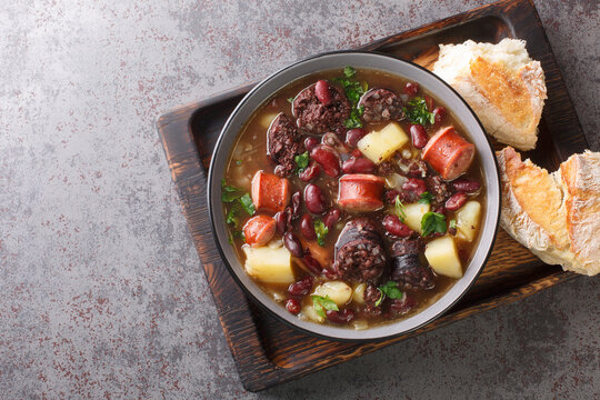 Sopa de pedra Portuguese Stone Soup combination of beans and sausages such as chouri&ccedil;o and morcilla close up in the plate on the table. Horizontal top view from above