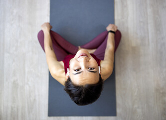 Attractive Asian woman practices the concept of yoga, sits in an exercise on a yoga mat, Balasana pose, exercises, wears sportswear, sleeveless T-shirt and pants, full length, white attic background.