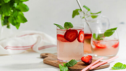 Homemade refreshing strawberry lemonade in glasses and jug with fresh strawberries and mint leaves. Summer drink 