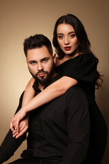 Handsome bearded man with sexy lady on light brown background