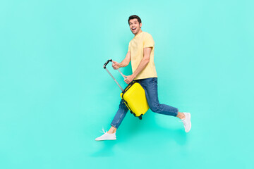 Full length profile photo of funky brunet guy run with bag wear t-shirt jeans shoes isolated on teal background
