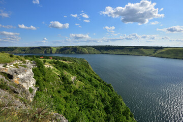 The panoramic landscape of Bakota Bay view. Dniester river, Ukraine. The banks of a large river with small waves on the water. Panoramic river, high banks, green hills. Summer day.