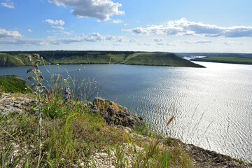 The panoramic landscape of Bakota Bay view. Dniester river, Ukraine. The banks of a large river with small waves on the water. Panoramic river, high banks, green hills. Summer day.