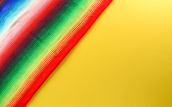 Cinco de Mayo holiday background made from mexican blanket stripes or poncho serape on yellow background.