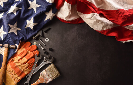 Happy Labor day concept. American flag with different construction tools on dark stone background.