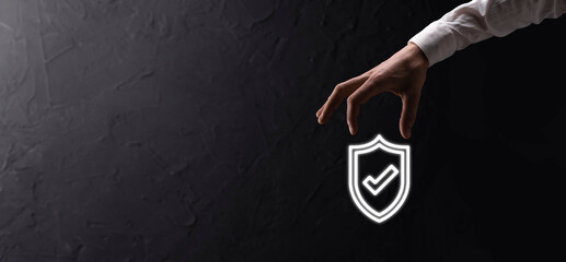 Male hand holding protect shield with a check mark icon on blue background. Protection network security computer and safe your data concept .