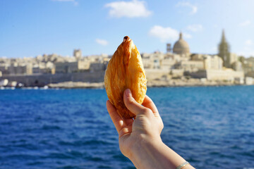 Traditional savoury pastry Pastizzi from Malta with Valletta old town on background, Malta Island