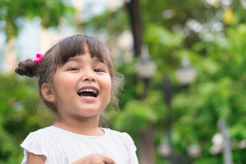 Happy cute little girl happily laughing in green summer park