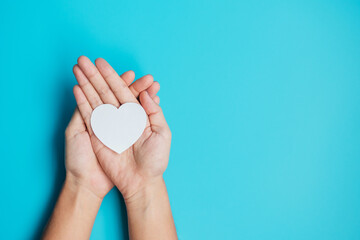 hands holding paper Heart on blue background. Donation, Wellness, world Heart day, world Health day and Happy Valentines day concepts