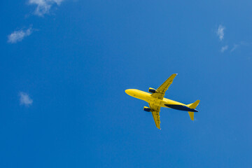 Yellow-blue passenger plane flies in the blue sky, air transportation concept, population evacuation