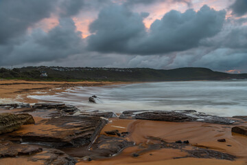 Soft sunrise seascape with rocks and rain clouds