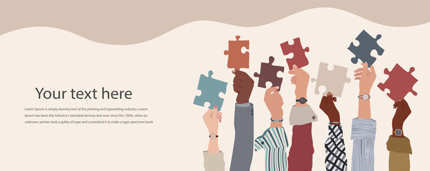 Group of multicultural business people with raised arms holding a piece of jigsaw. Colleagues of diverse ethnic groups and cultures. Cooperate - collaborate. Concept of teamwork.Copy space