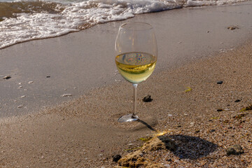 Romantic glass of white wine, on the sea beach. Wine tasting and relaxation at the resort