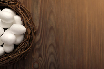 White chicken eggs in a nest on a wooden background. Top view. Free space. Easter eggs. High quality photo