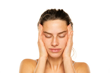 Young woman tightening her face skin with her palms on a white background