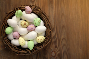 Colored chicken and quail eggs in a nest on a wooden background. Top view. Free space. Easter eggs. High quality photo