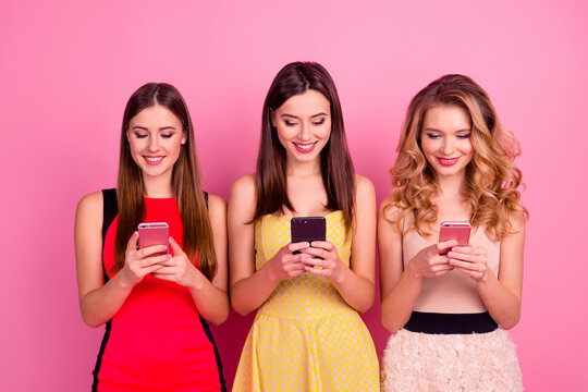 Photo of three cheerful gorgeous girls hold use telephone chatting typing isolated on pink color background