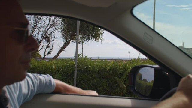 01.10.2021 Via Roca, Melendugno, Italy. driver is driving car Travels in Pulia. City road with parking on the right. Palm trees adorn the town 